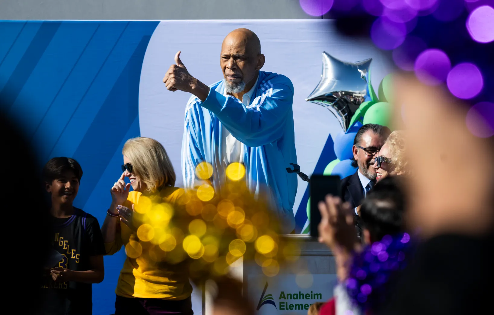 Lakers legend Kareem Abdul-Jabbar gives the thumbs up as students cheer with pom-poms at Edison Elementary School in Anaheim, CA on Wednesday, November 19, 2025. Abdul-Jabbar announced a partnership between his Skyhook Foundation and the Orange County Department of Education’s Inside the Outdoors to expand environmental science STEM learning programs. More than 3,000 pairs of Adidas shoes and backpacks were donated to students in the Anaheim Unified School District. (Photo by Paul Bersebach, Orange County Register/SCNG)
