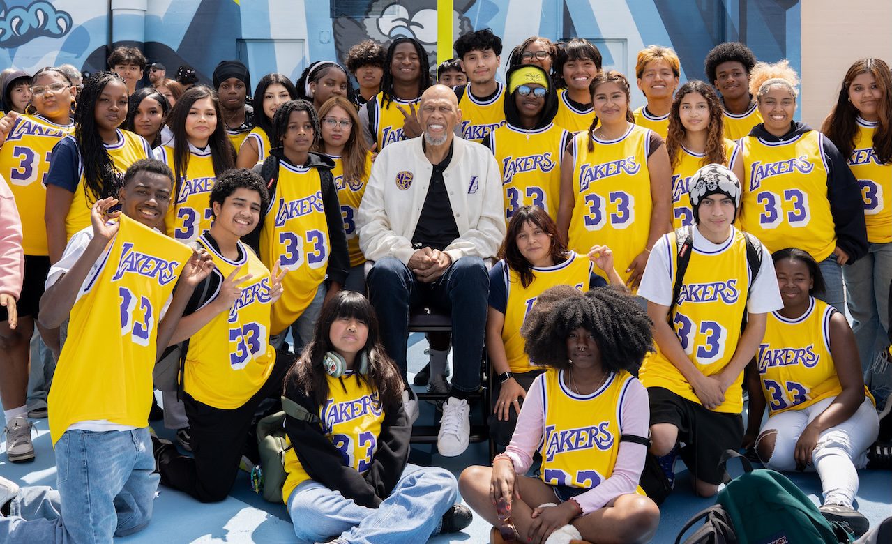 Kareem surrounded by students in 33 Lakers jerseys