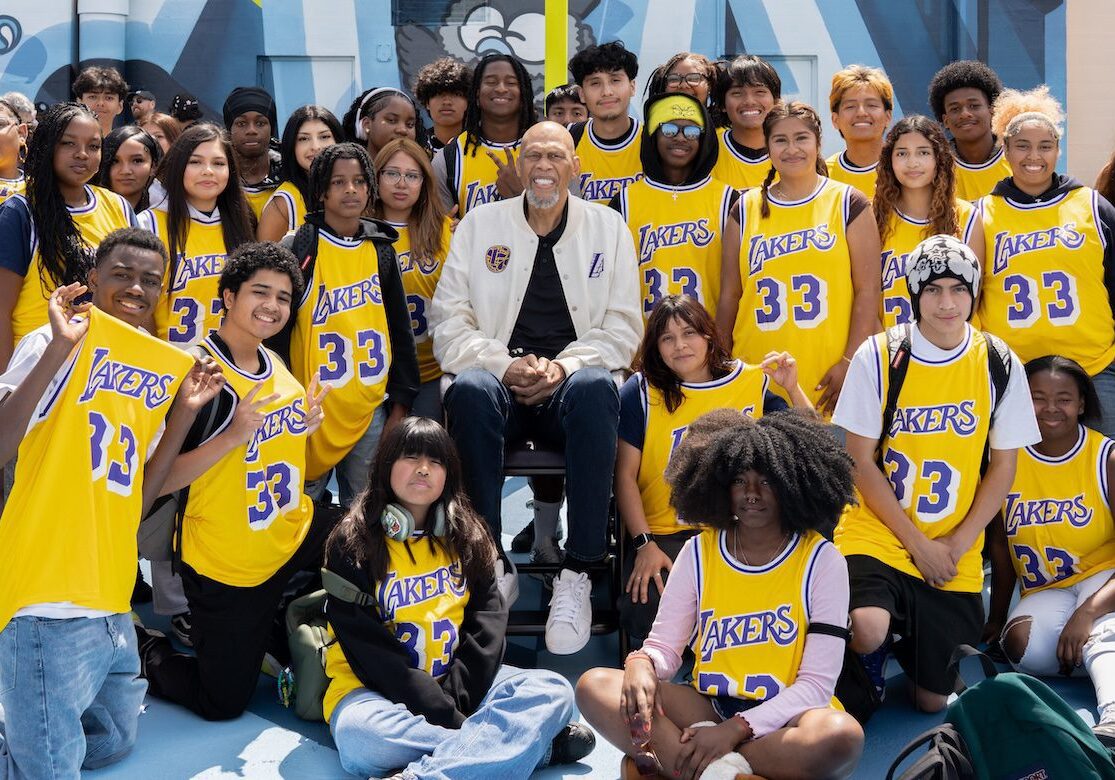 Kareem surrounded by students in 33 Lakers jerseys